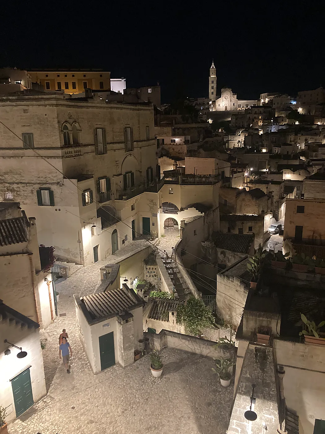 Vicoli, scale e tetti dei Sassi di Matera di notte, con il Duomo illuminato in cima al colle.