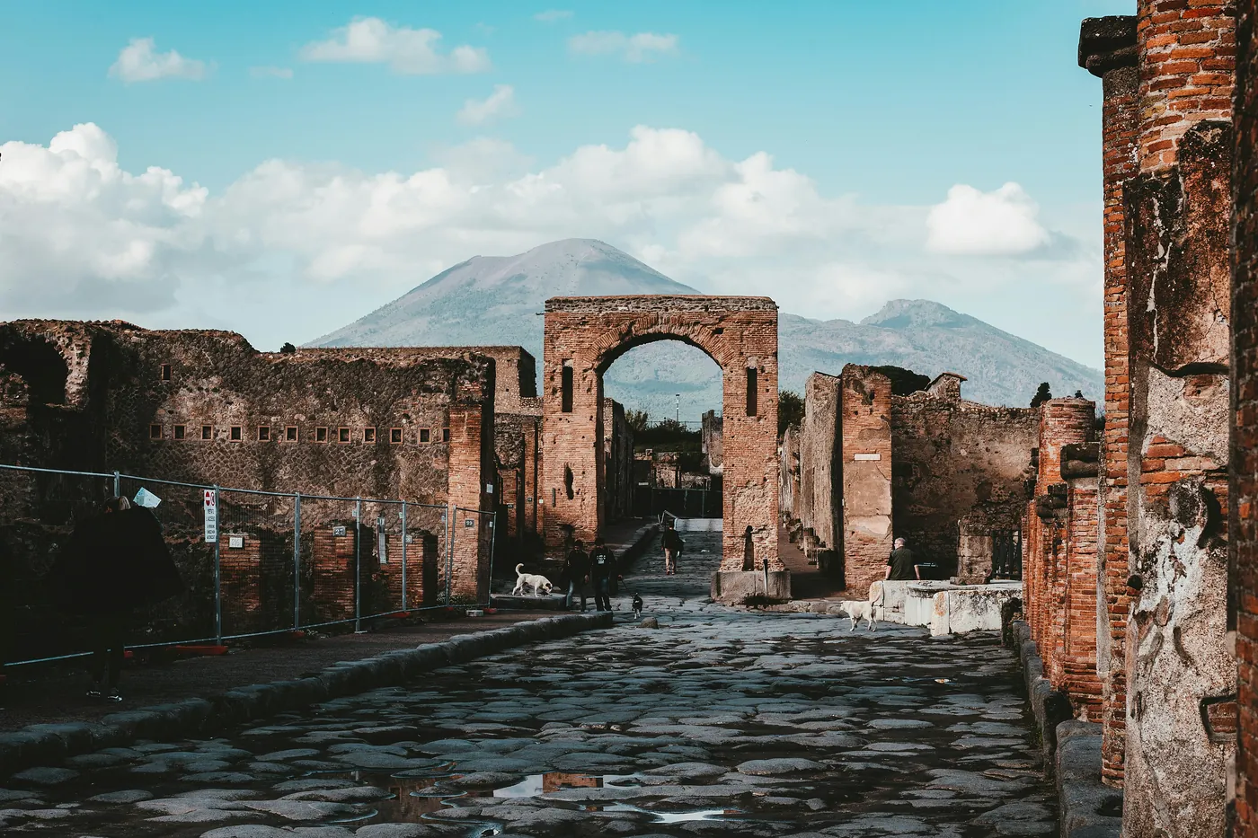 Una strada lastricata degli scavi di Pompei con un arco e il Vesuvio sullo sfondo