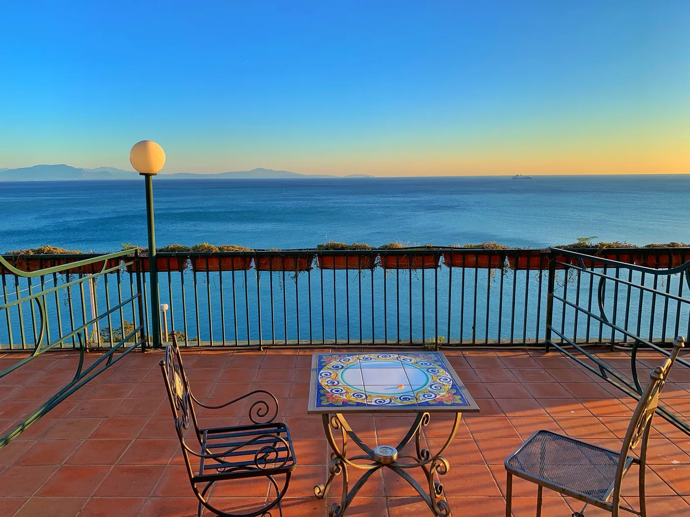 Una terrazza con sedie in ferro battuto affacciata sul mare della Costiera Amalfitana alle prime luci