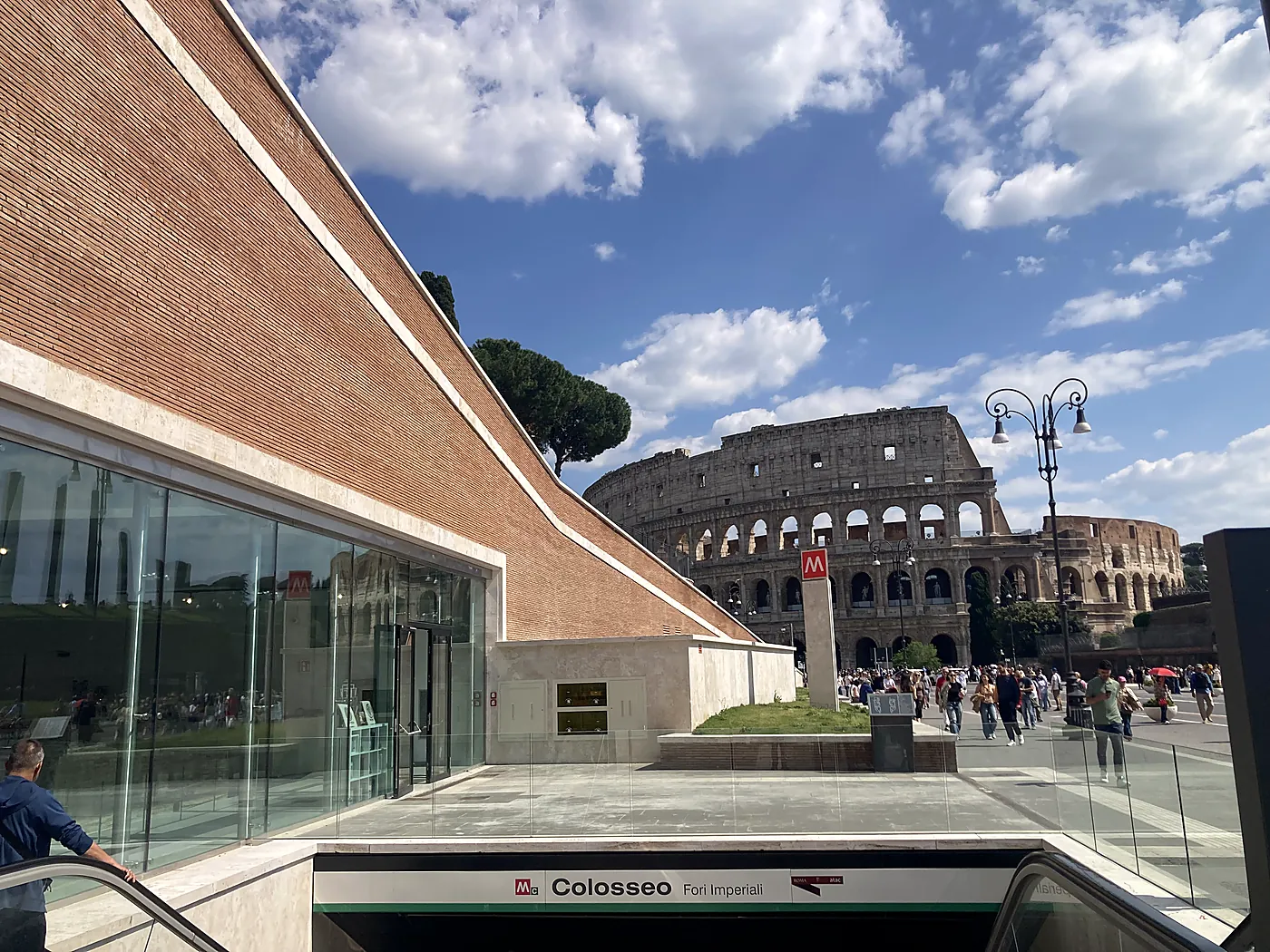 Il Colosseo visto dall'uscita della stazione Colosseo–Fori Imperiali della Metro C, con la sua parete in mattoni in primo piano.