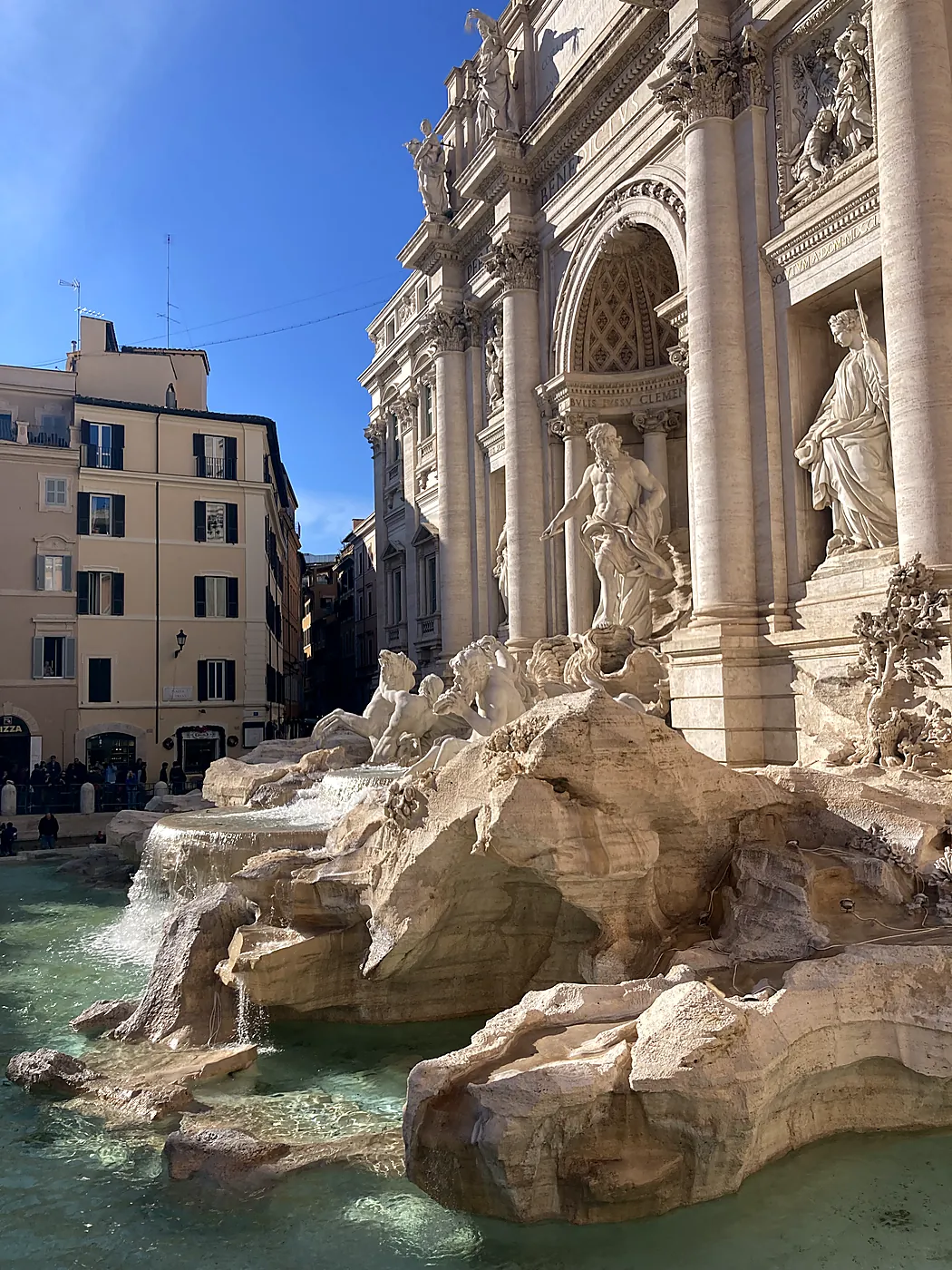 La Fontana di Trevi a Roma vista di scorcio, con Oceano sul carro, i cavalli marini e l'acqua che scorre sugli scogli di travertino.