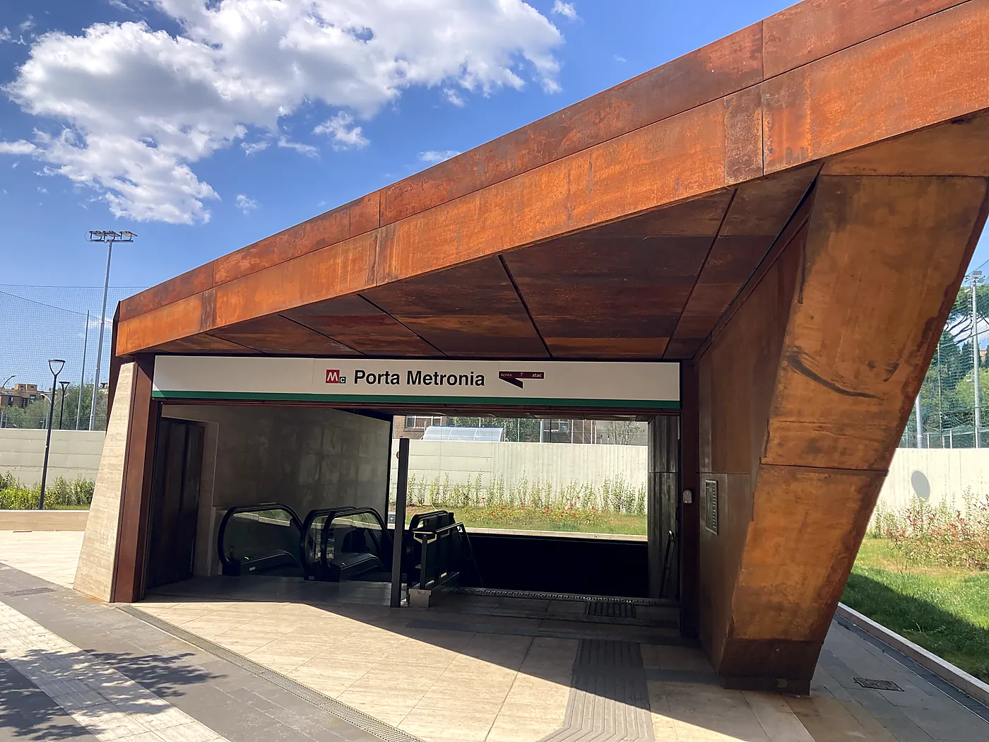 L'ingresso in acciaio corten della stazione Porta Metronia della Metro C di Roma, sotto un cielo con nuvole.