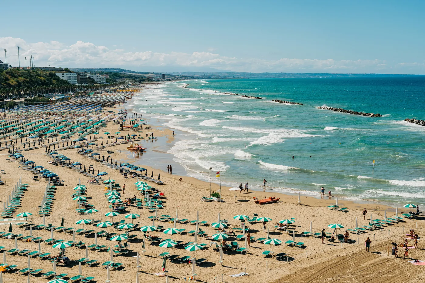 Una lunga spiaggia con file di ombrelloni e le onde dell'Adriatico, d'estate