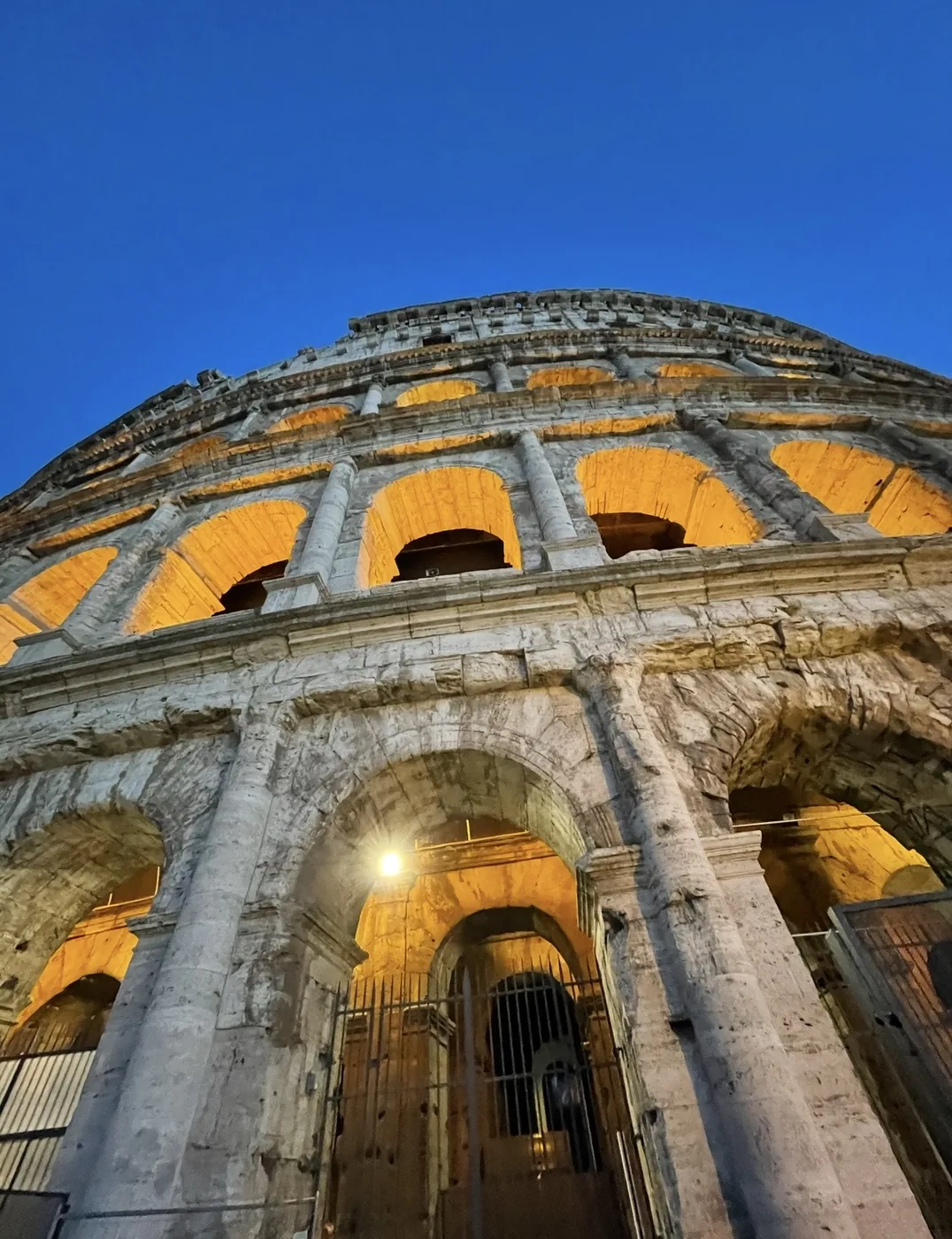 Le arcate esterne del Colosseo viste dal basso, dorate al tramonto