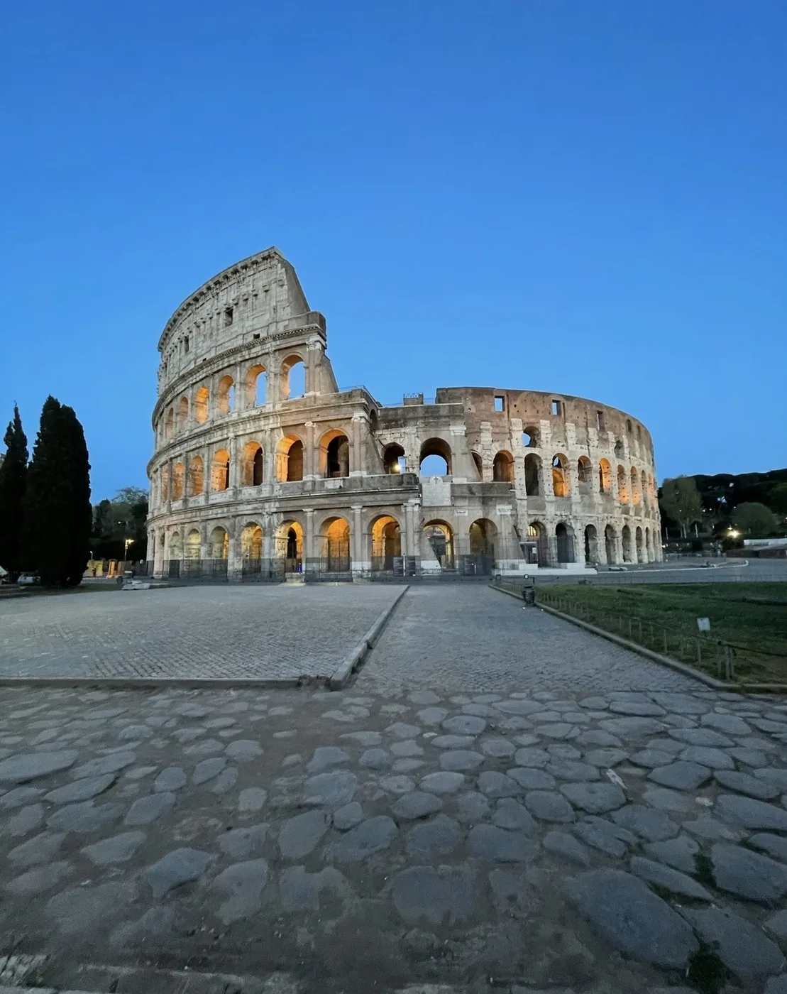 Il Colosseo illuminato dall'interno all'imbrunire, i sampietrini vuoti davanti