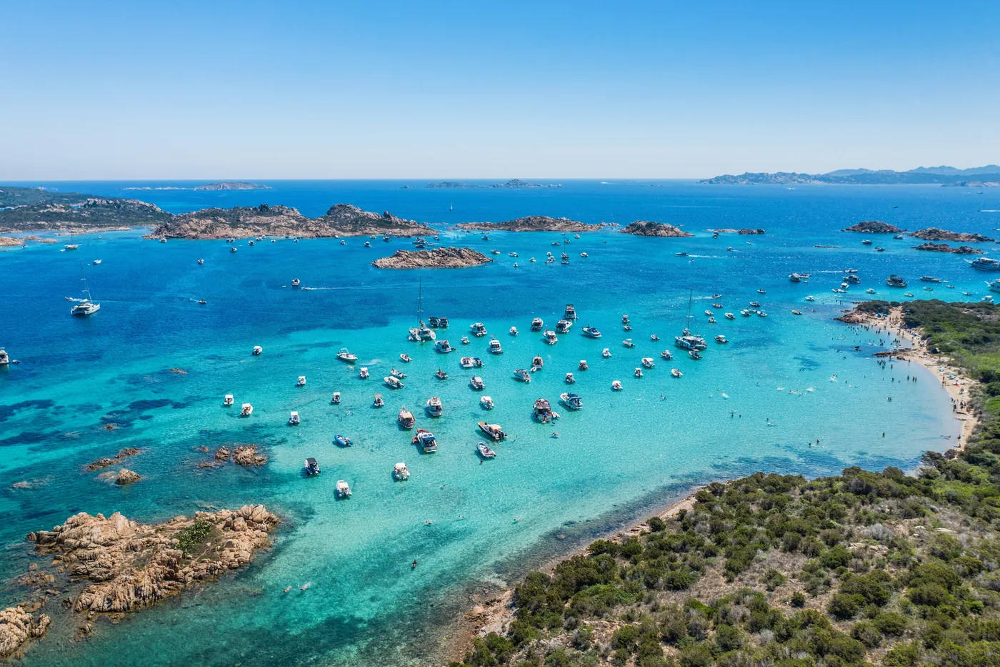Isolotti di granito e barche ancorate in un mare turchese, visti dall'alto