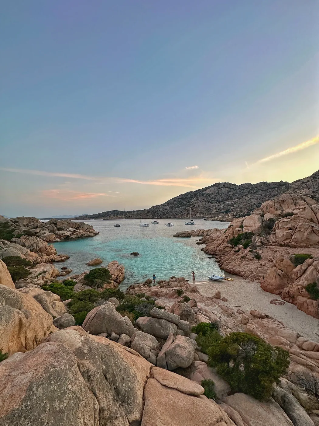Una cala turchese fra le rocce di granito rosa della Sardegna al tramonto
