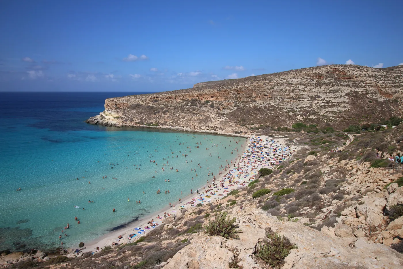La Spiaggia dei Conigli a Lampedusa, con la sabbia bianca e l'acqua turchese piena di bagnanti