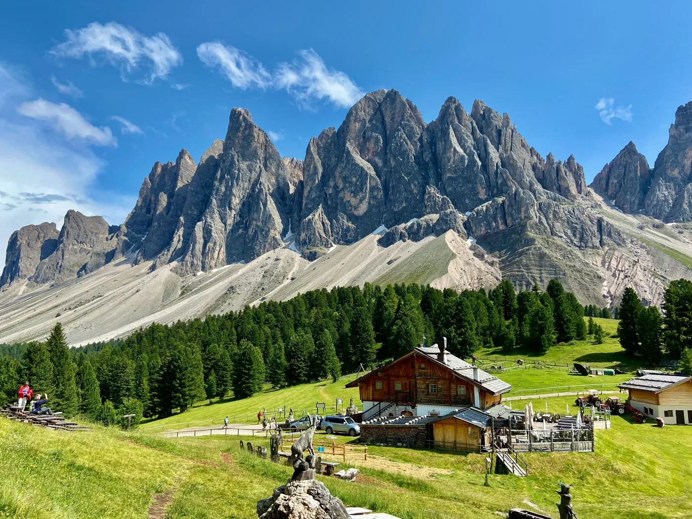 Le cime delle Odle sopra i boschi e una malga di legno in Val di Funes