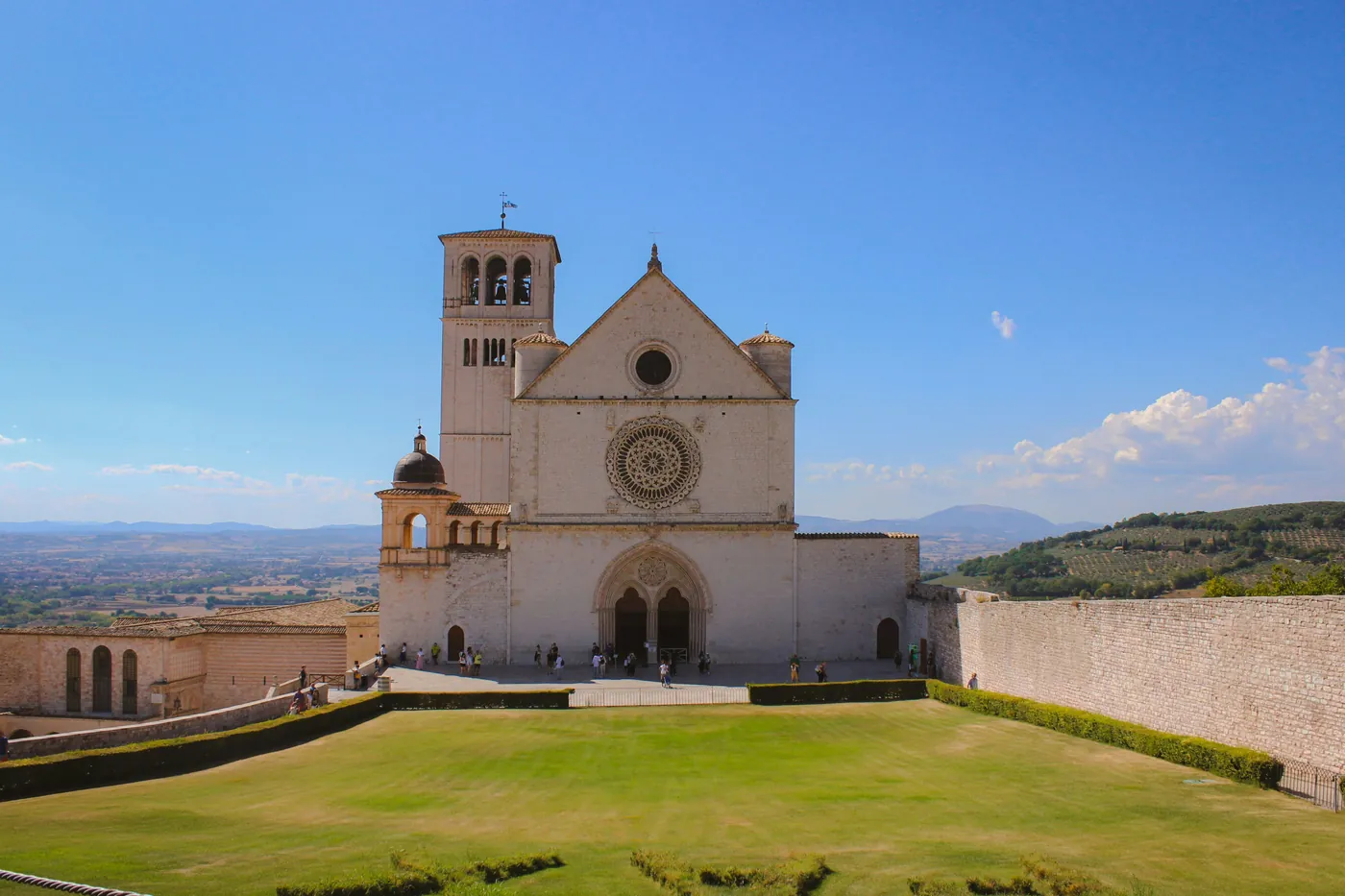 La facciata della Basilica superiore di San Francesco ad Assisi con il campanile e il prato davanti