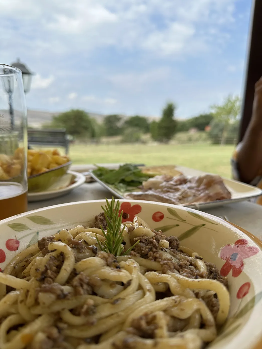 Un piatto di pici su un tavolo con la campagna sullo sfondo