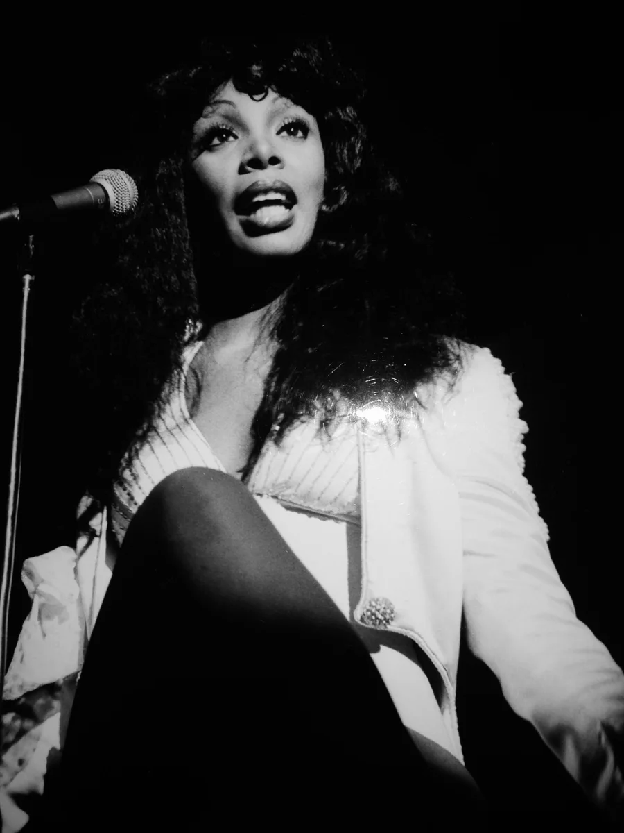 Donna Summer canta al microfono sul palco del Teatro Sistina, in giacca bianca, fotografata dal basso