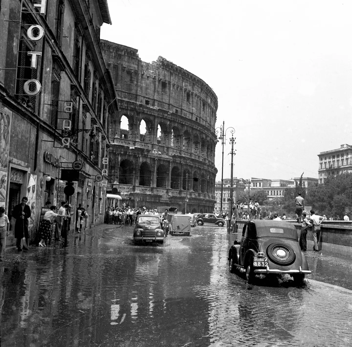 Automobili che guadano la strada allagata davanti al Colosseo dopo un nubifragio