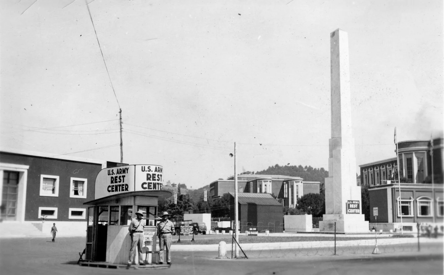 Il chiosco del U.S. Army Rest Center visto da lontano, con un obelisco e i palazzi razionalisti sullo sfondo