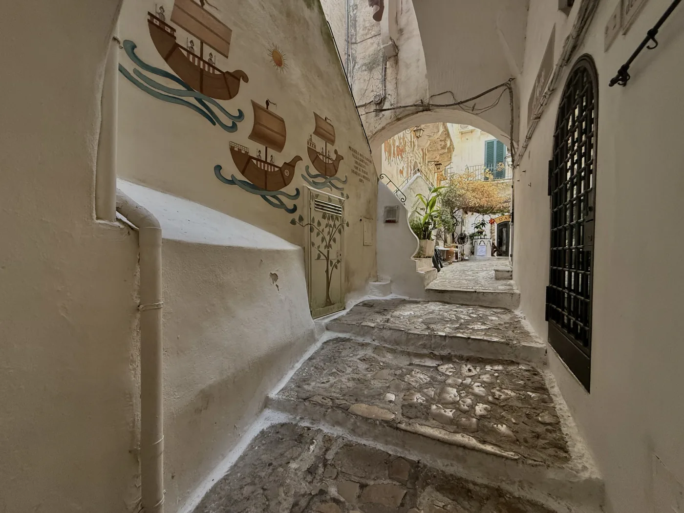 Un vicolo bianco del borgo con il murale delle tre navi