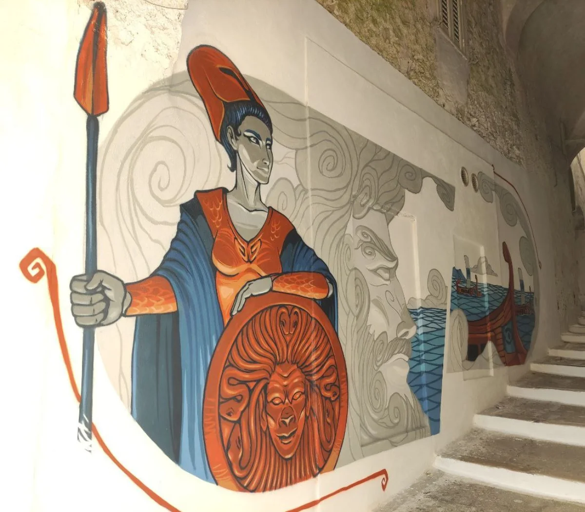 Il murale di Atena e della nave di Telemaco, dipinto sul muro sotto l'arco che precede via Lebina