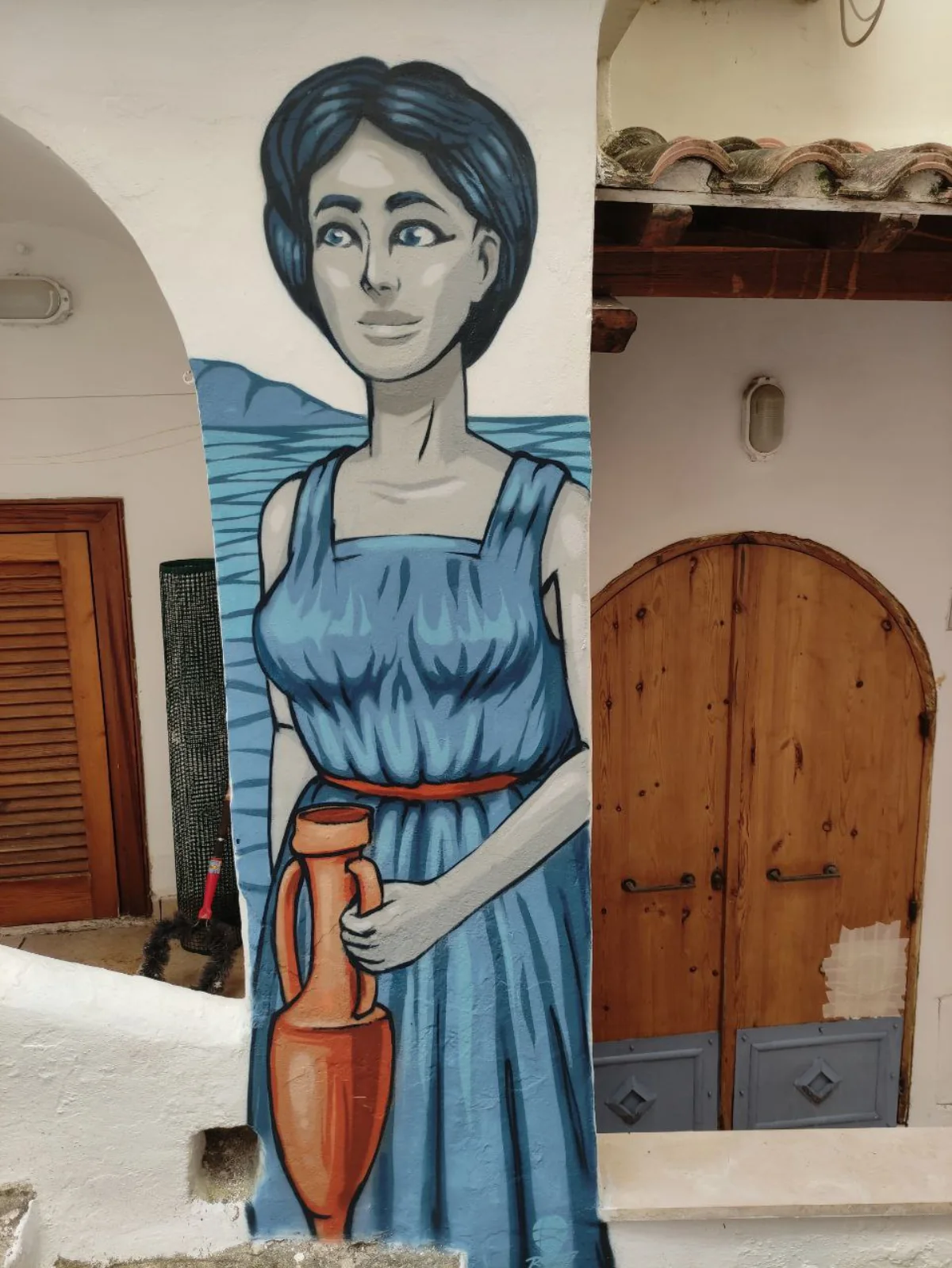 Il murale di Nausicaa con un vestito blu e un'anfora d'argilla, sullo sfondo del mare