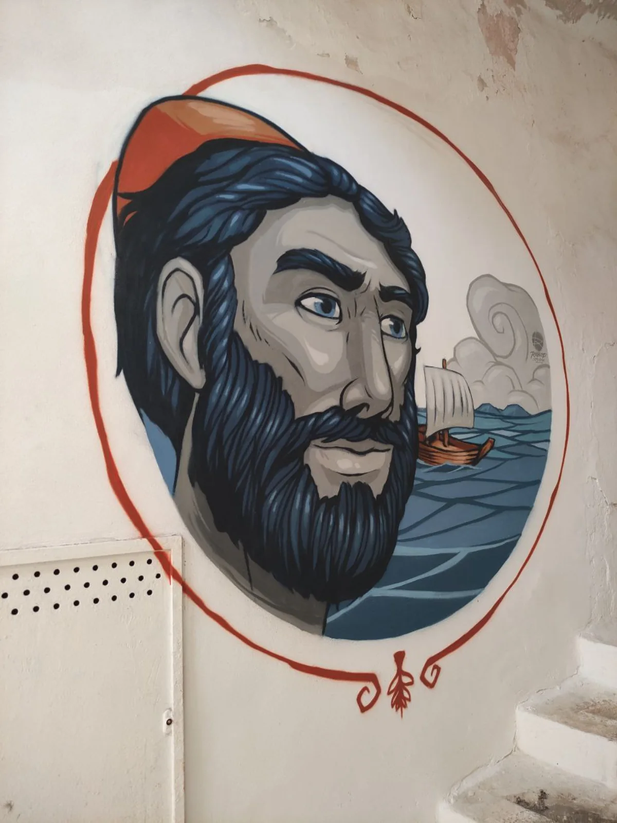 Il murale di Ulisse in primo piano con il copricapo, e alle sue spalle la zattera con una vela di fortuna
